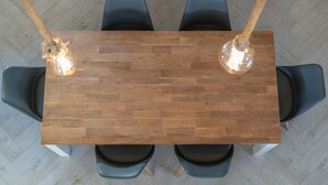 Ein rechteckiger Holztisch mit vier Stühlen, zwei Pendelleuchten und einem Parkettboden mit Fischgrätenmuster.