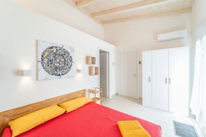 A bedroom with a bed, a door, a wardrobe, and an air conditioning unit.