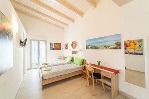 A room with a bed, desk, chair, and artwork on the walls.