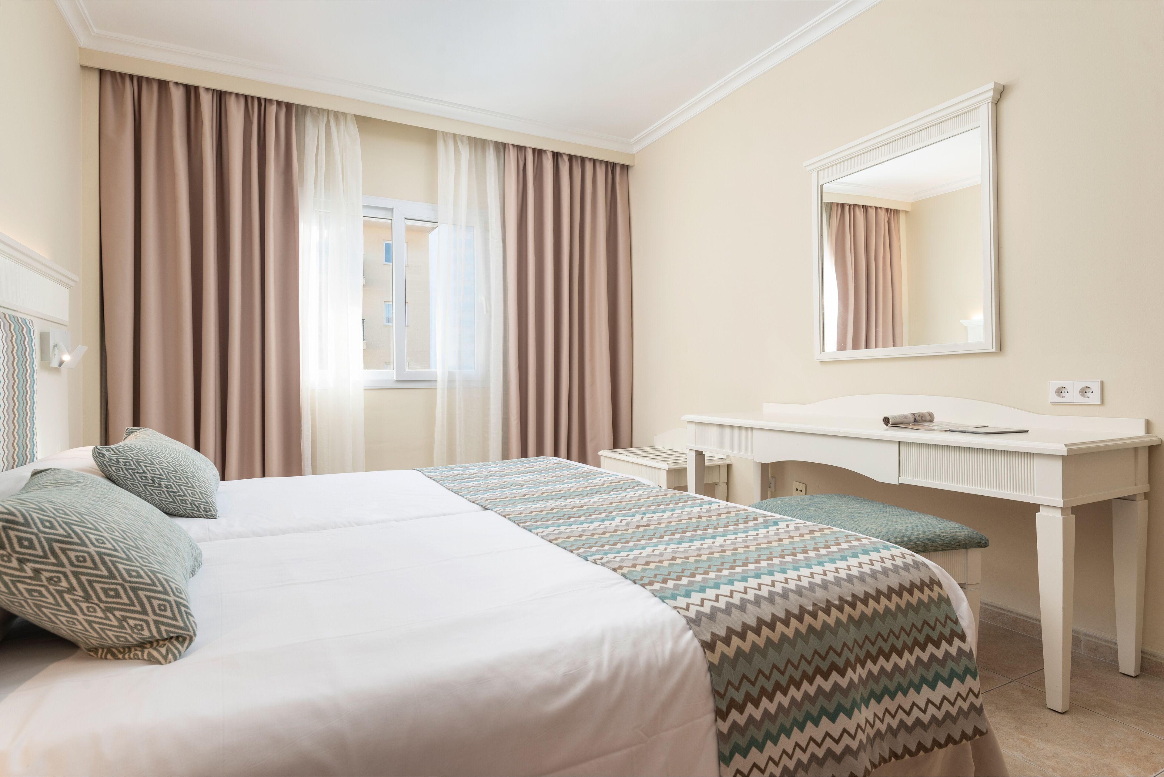 Habitación de hotel con una cama grande, un escritorio y un espejo.