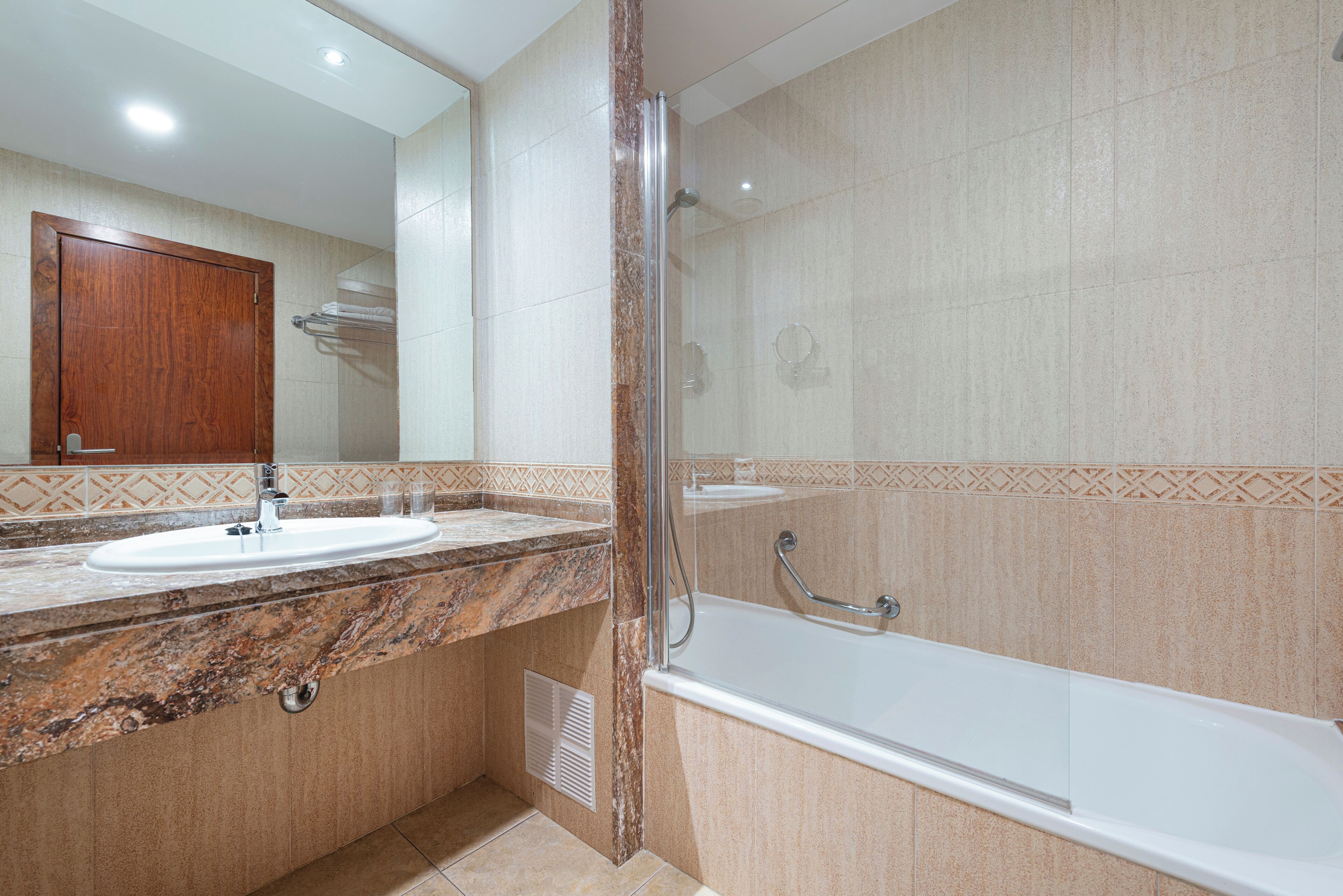 A bathroom with a marble sink, a glass shower enclosure, and a bathtub.