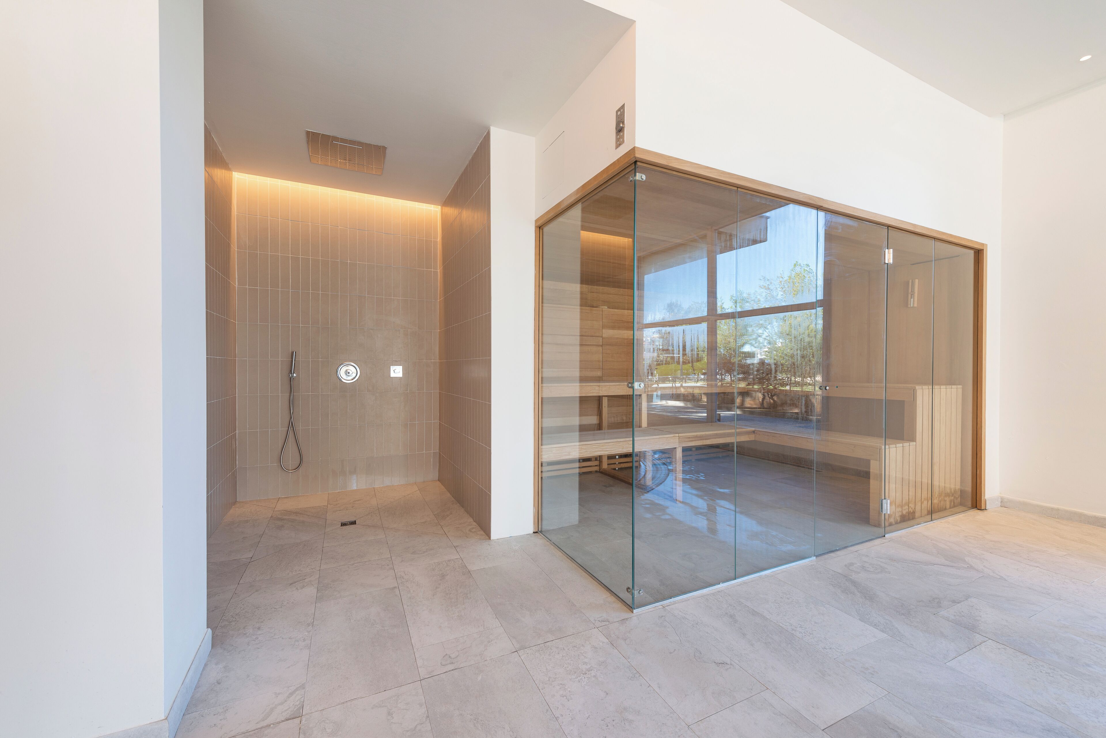 A modern bathroom with a glass shower enclosure, a visible showerhead, and a tiled floor.