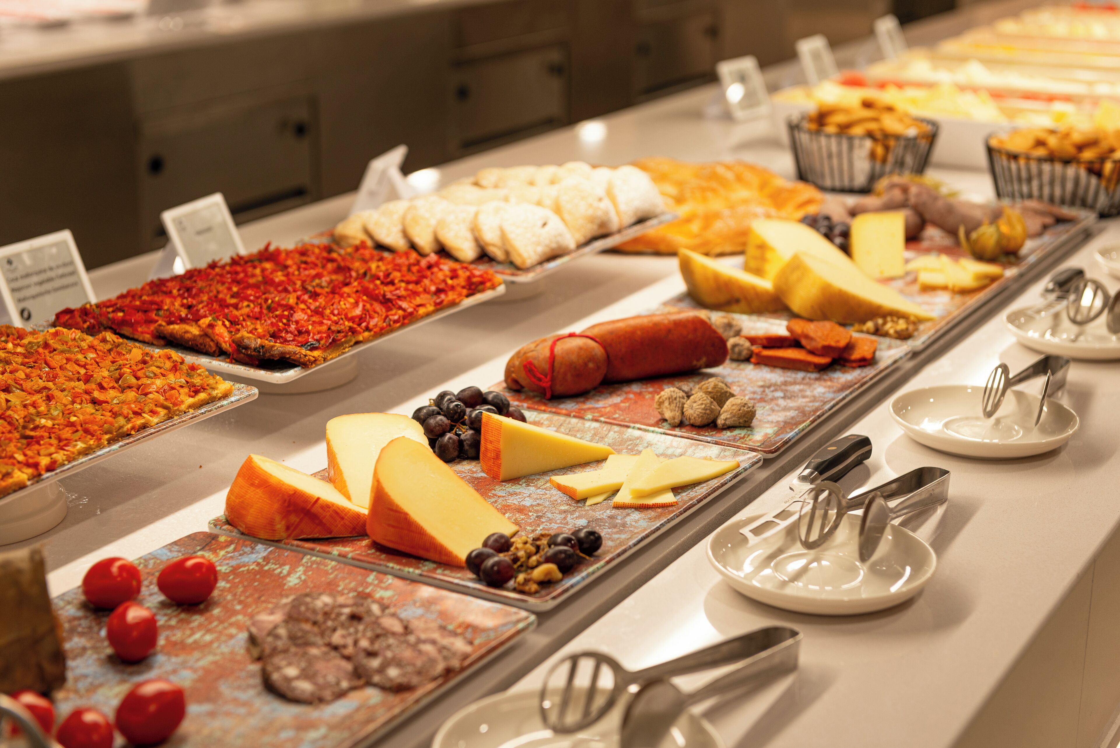 Ein Buffet mit verschiedenen Speisen, darunter Pizza, Käse und Fleisch.