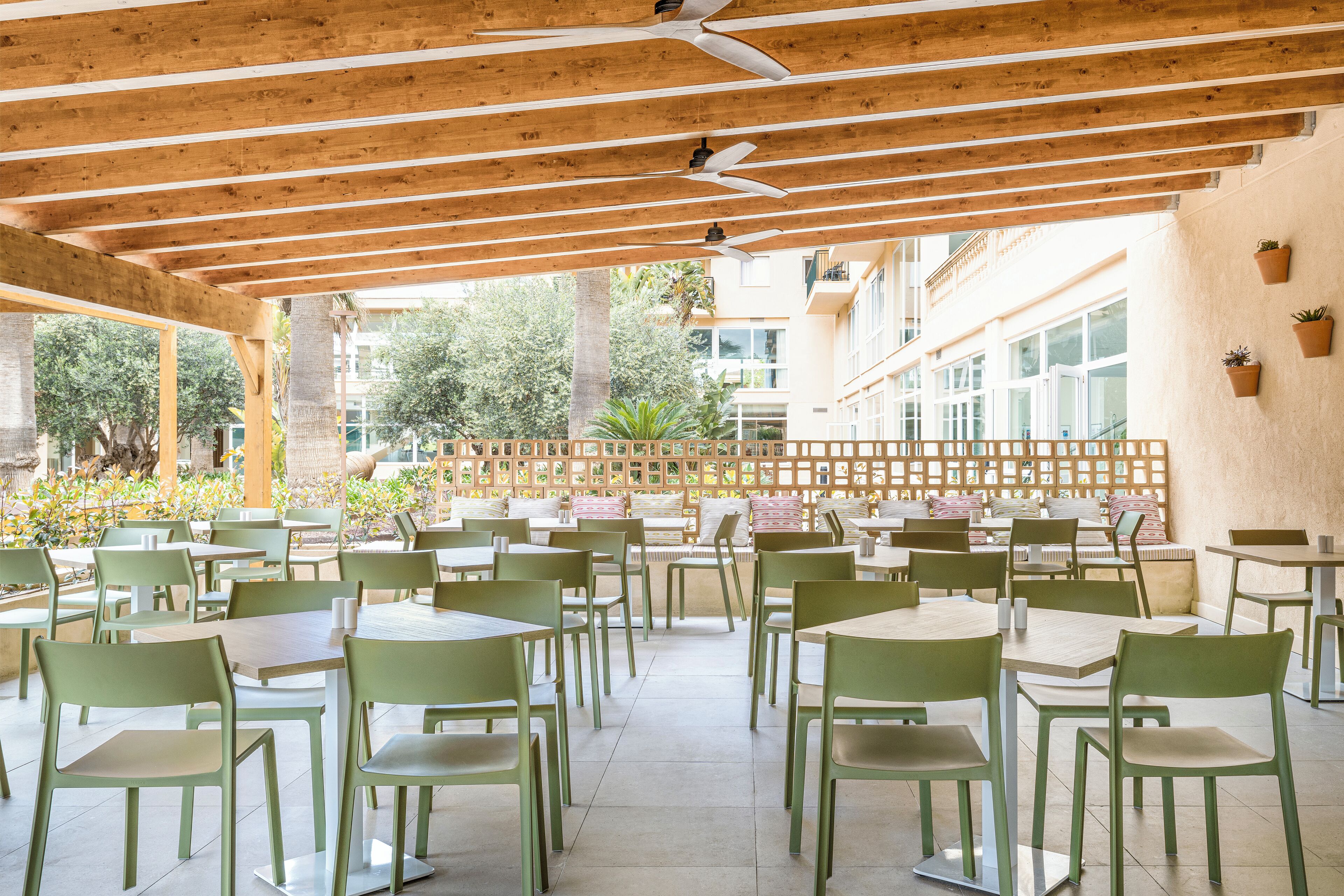 Un café en plein air avec des poutres en bois, des chaises vertes et des tables.