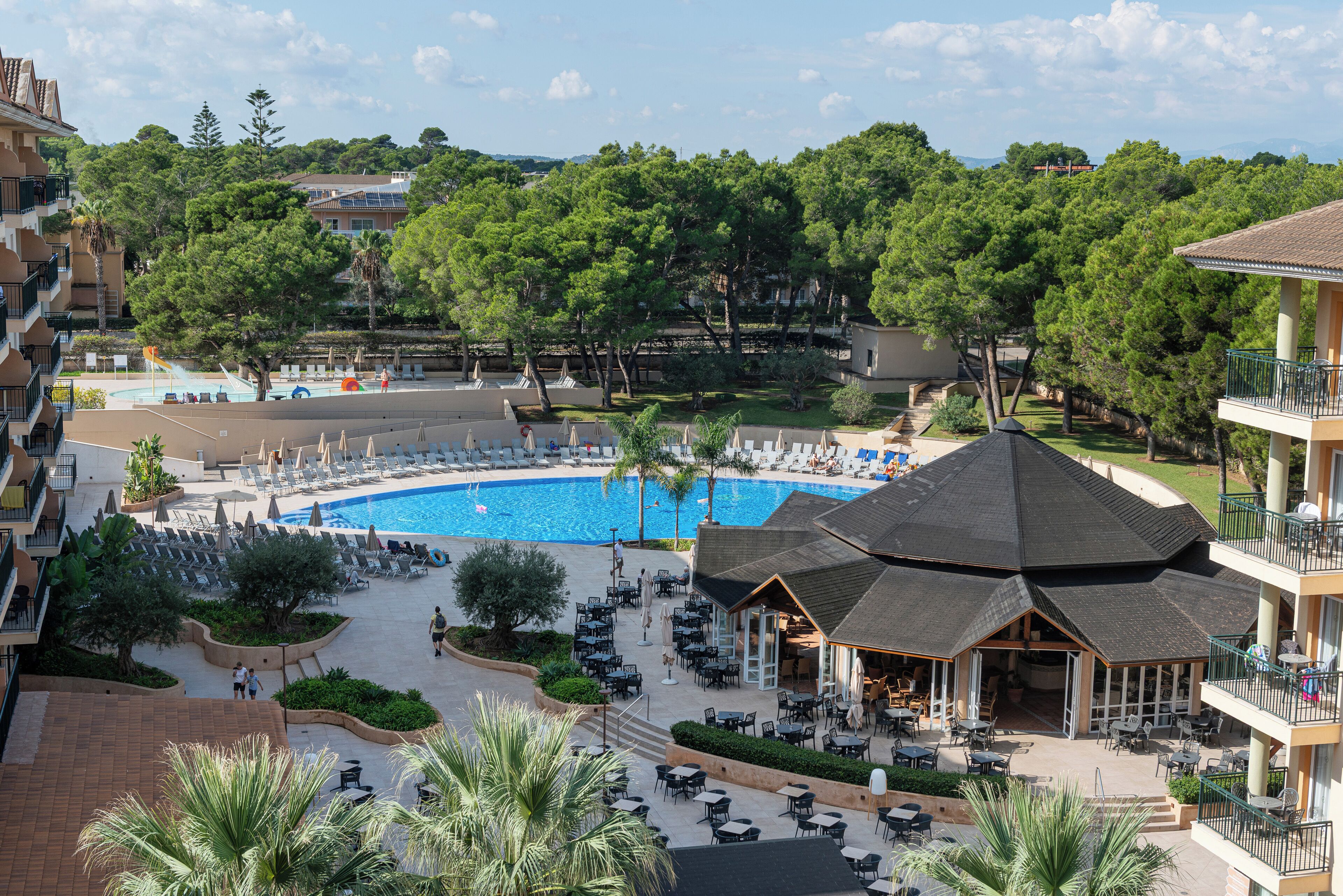 A resort with a swimming pool, outdoor seating, and a covered dining area.