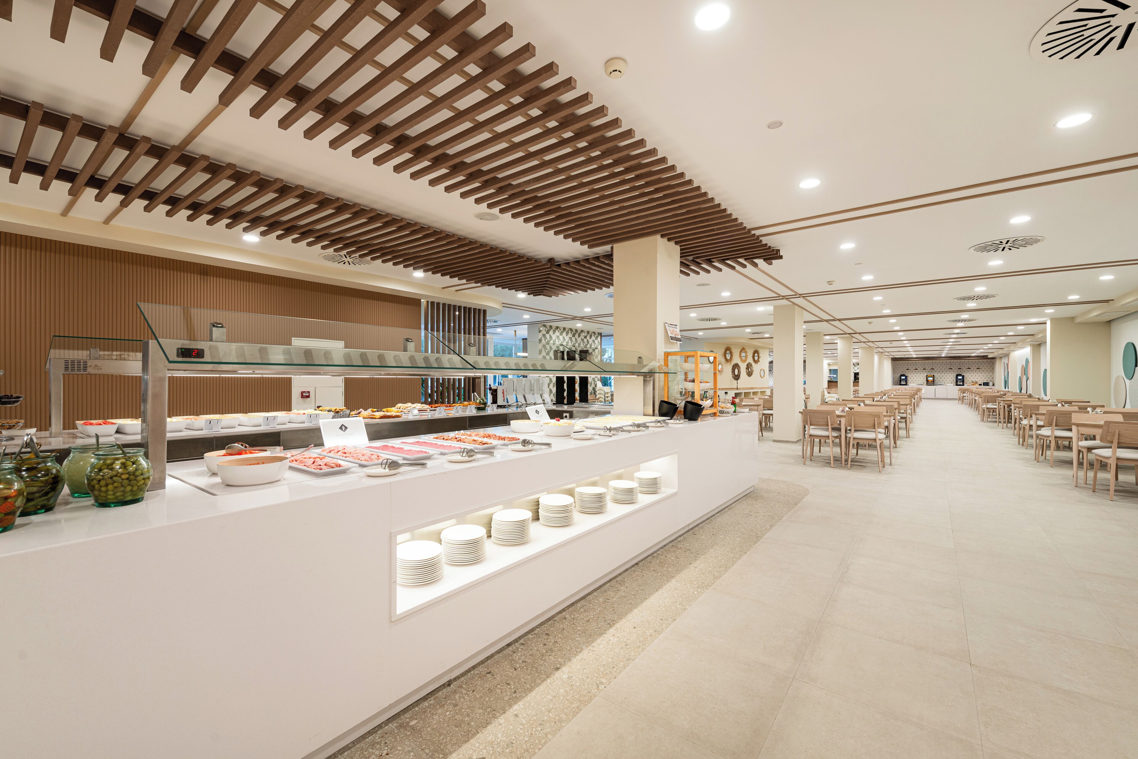 A buffet area with a variety of food items, a seating area with chairs, and a modern ceiling design.