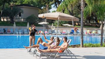 Zona de piscina con sillones de descanso, sombrillas y socorrista.