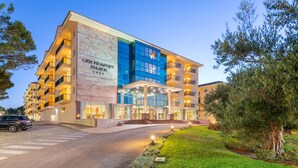 A multi-story hotel with a prominent entrance, a parking area, and a well-maintained lawn. - Aparthotel Can Picafort Palace (Santa Margalida)