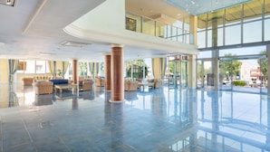 A spacious lobby with a high ceiling, large windows, and a central seating area with sofas and chairs. - Aparthotel Can Picafort Palace (Santa Margalida)