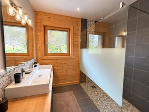 Un baño con pared de madera, un espejo grande, un lavabo y una zona de ducha.