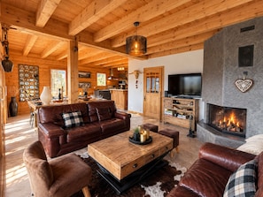Una sala de estar acogedora con chimenea, mobiliario de cuero y televisor.