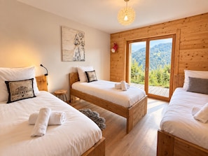 A room with three wooden beds, a large window with a mountain view, and a painting on the wall. - Family chalet in Les Gets, quiet, parking, 8 people (Les Gets)
