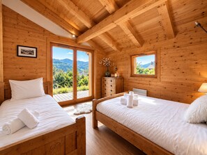 Un dormitorio de cabaña de madera con dos camas, un aparador y vistas al exterior.