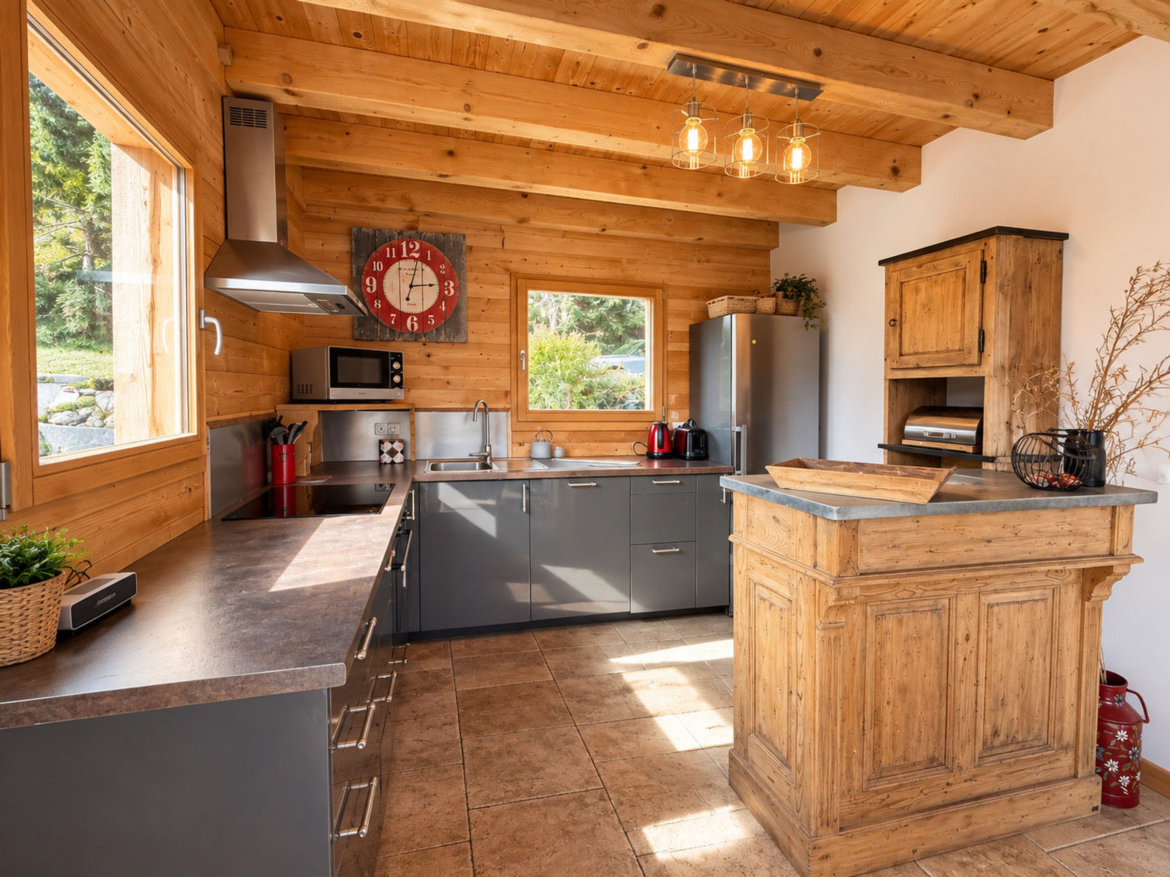 A modern kitchen with wooden walls, a central island, stainless steel appliances, and a large clock on the wall.