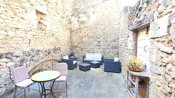 A stone-walled courtyard with outdoor seating including a round table and chairs, and a sofa set. - Duplex with terrace & patio – old town Saint-Paul-Trois-Châteaux (Saint-Paul-Trois-Châteaux)