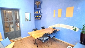 A room with a wooden table and chairs, a blue wall, and a door with glass panels. - Duplex with terrace & patio – old town Saint-Paul-Trois-Châteaux (Saint-Paul-Trois-Châteaux)