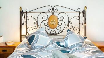 Una cama con cabecera de metal, una placa de madera y ropa de cama a rayas.