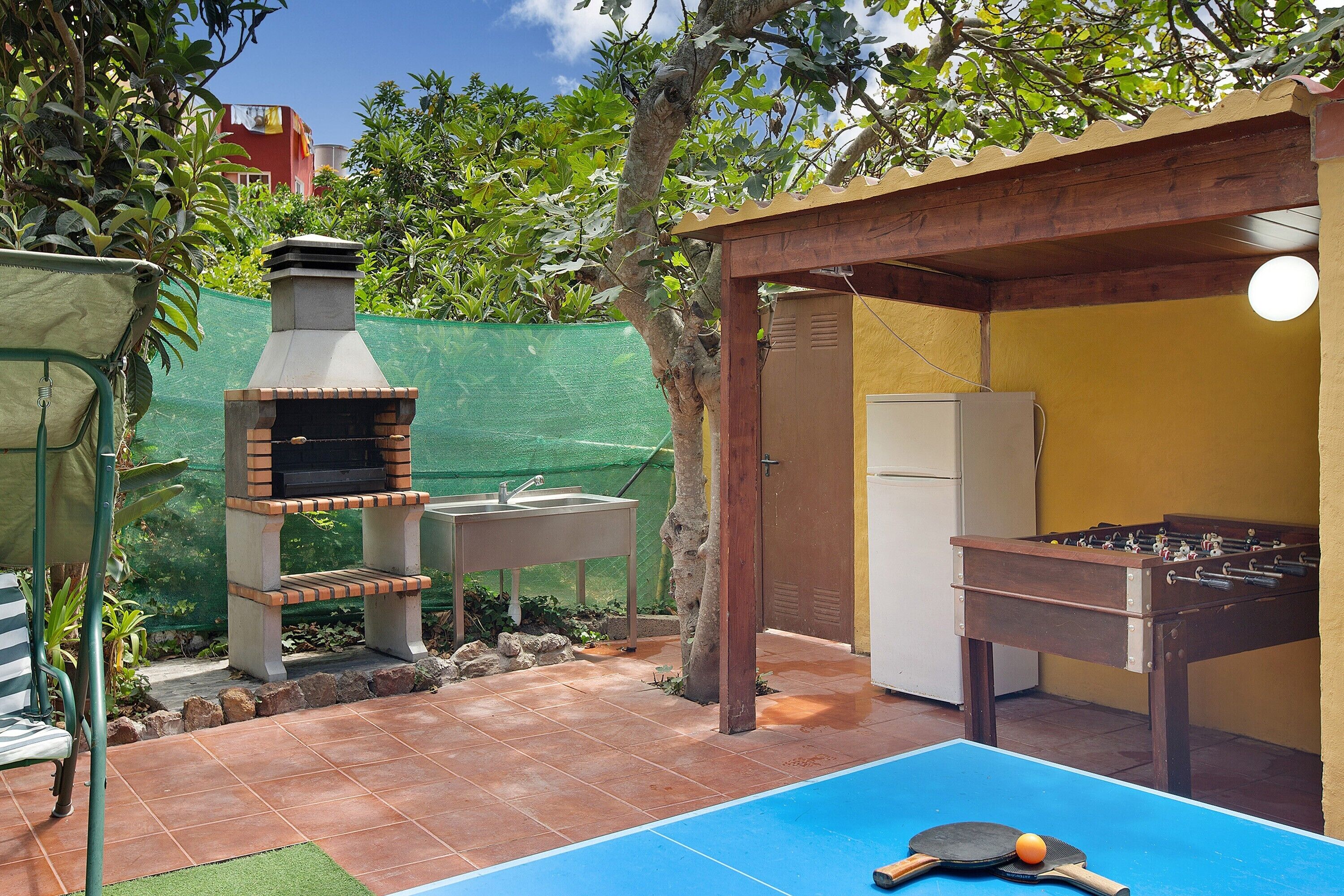 Eine Terrasse im Freien mit einem Grill, einem Tischkicker und einem Pingpongtisch.
