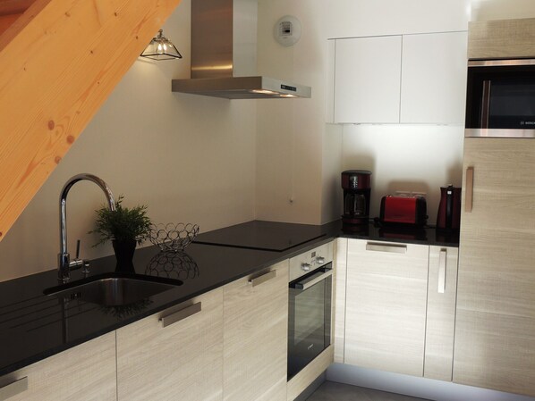 Una cocina moderna con encimera negra, pileta de acero inoxidable y muebles de madera.