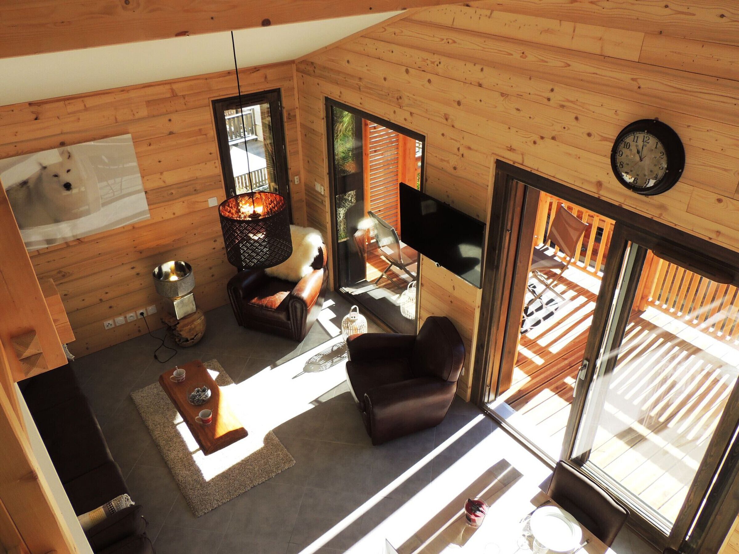 Un intérieur de chalet chaleureux avec des murs en bois, une cheminée, un téléviseur et une grande fenêtre.