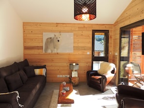 Un accogliente soggiorno con finiture in legno, un'ampia cornice con ritratto di un cane, una poltrona in pelle e un tavolino da caffè con tazze e una ciotola.