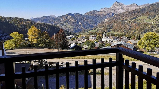 Un pueblo de montaña con casas tradicionales, una iglesia y vistas de las montañas circundantes.