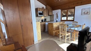 Una cocina acogedora con armarios de madera, un microondas y un comedor con mesa y sillas.
