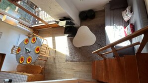 Un espacio habitable compacto con comedor, sofá y escalera.