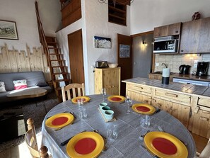 Een eethoek met een ronde tafel voor zes personen, houten kasten, een magnetron en een koffiezetapparaat.