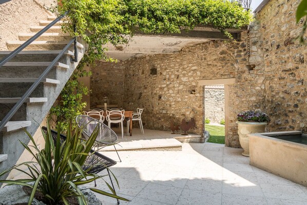 A stone courtyard with a staircase, outdoor seating, and a potted plant.