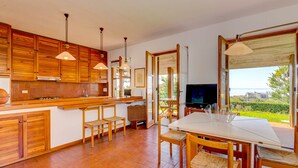 A spacious kitchen with wooden cabinets and a large dining area with a TV and outdoor view.
