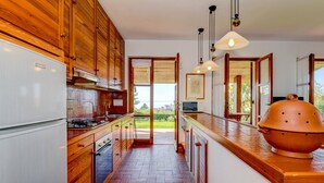 A modern kitchen with wooden cabinets, a large island, and a view of the outdoors.