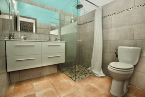 A modern bathroom with a glass-enclosed shower, a white toilet, and a vanity with drawers. - 5-Bedroom Villa • Infinity Pool • 180° Ocean View (Le Diamant)