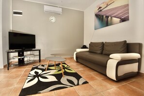 A living room with a flat-screen TV, a sofa, a coffee table, and a patterned rug.