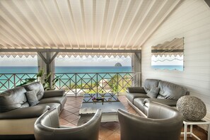 A cozy patio with a view of the ocean, featuring a sofa set and a coffee table.