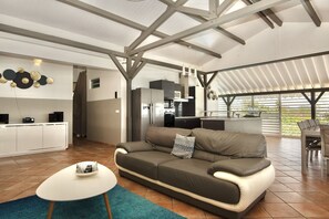 Un amplio salón con una cocina moderna, un sofá cómodo y un comedor con sillas.