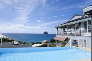 A pool with a view of the ocean and a building with a balcony.