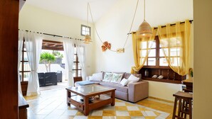 A living room with a sofa, coffee table, and a view of the outdoors. - Casa La Goleta, Volcán y Mar (Playa Blanca)