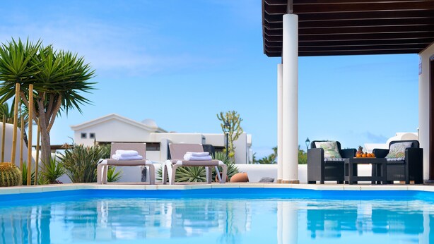 A pool area with lounge chairs and a covered seating area. - Casa La Goleta, Volcán y Mar (Playa Blanca)