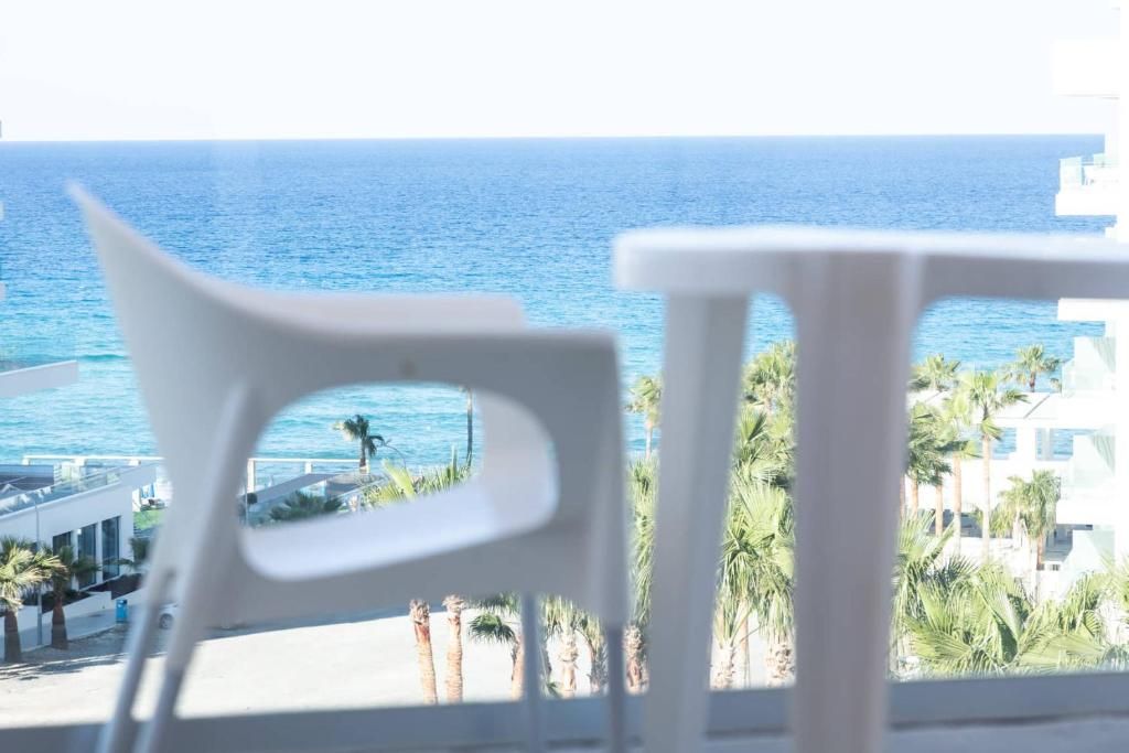 Vista desde un balcón sobre una playa con palmeras y un mar azul cristalino.