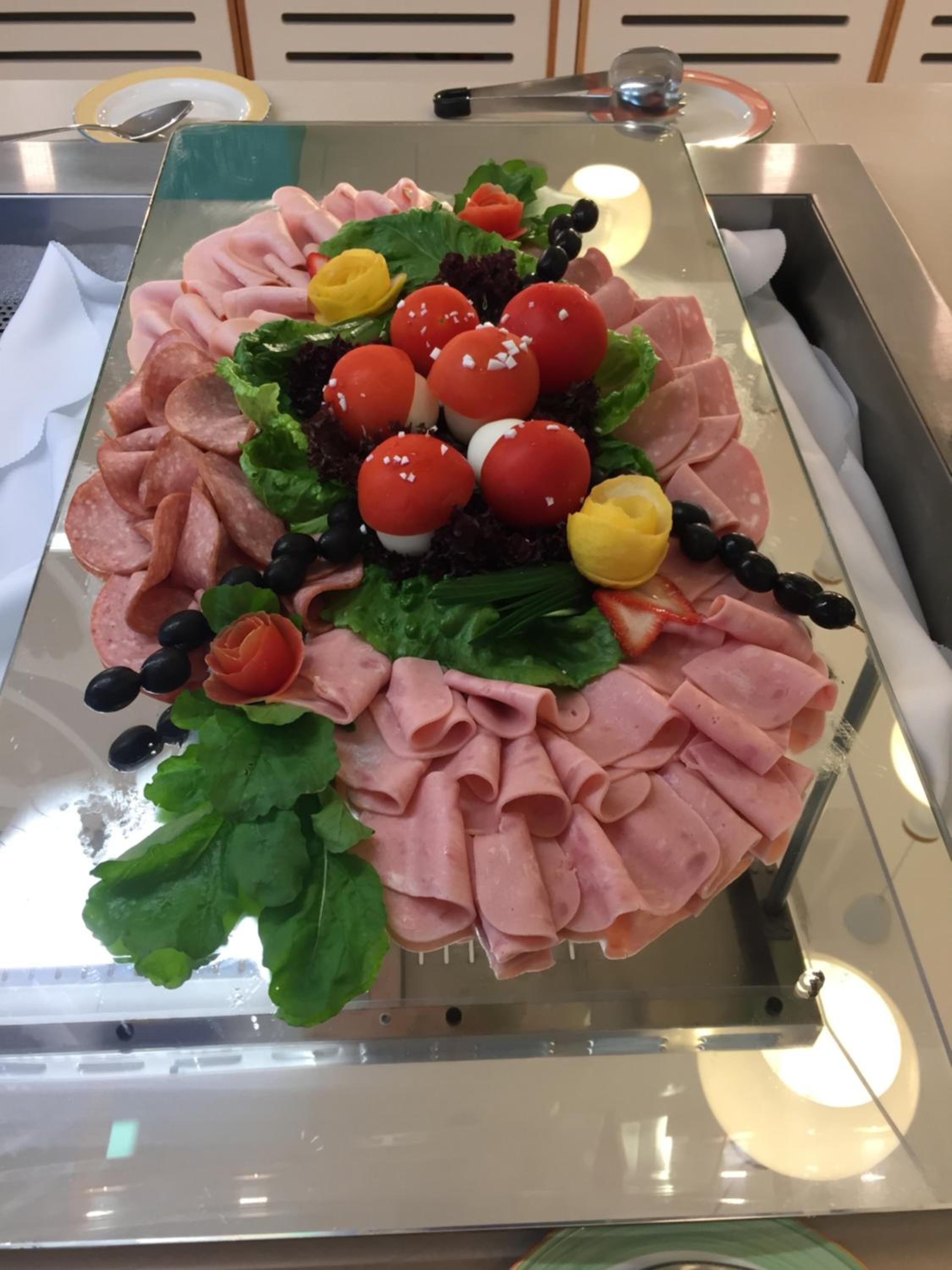 A charcuterie board with various meats, cheese, and garnishes.