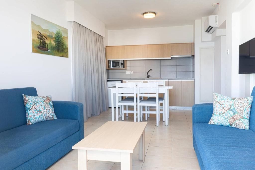 Ein modernes Wohnzimmer mit einer Couch, einem Couchtisch und einer Küche im Hintergrund.