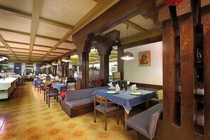 Un restaurante con vigas de madera, mesas con manteles azules y un suelo estampado.
