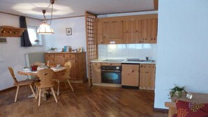 Eine kompakte Küche mit Holzschränken, einem Esstisch mit Stühlen und einem eingebauten Backofen.