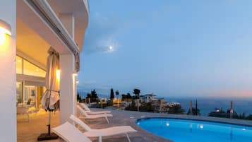 A poolside area with lounge chairs and a view of the sea.
