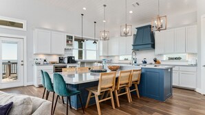 Een moderne keuken met witte kasten, een blauw eiland en houten stoelen.