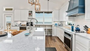 Een moderne keuken met witte kastjes, een groot kookeiland en uitzicht op het buiten.