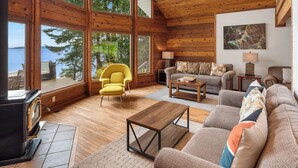 A spacious living room with large windows, a ceiling fan, and a fireplace. - Orcas Island, Aurora House #295 (Orcas Island)