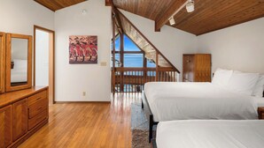 A bedroom with wooden floors, a large bed, a wooden wardrobe, and a painting of bicycles. - Orcas Island, Aurora House #295 (Orcas Island)