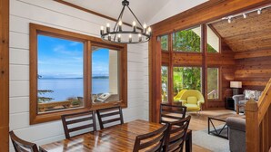 A wooden cabin with a dining area, large windows, and a view of a lake. - Orcas Island, Aurora House #295 (Orcas Island)
